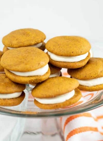 Pumpkin cookies with cream cheese frosting on a glass plate.