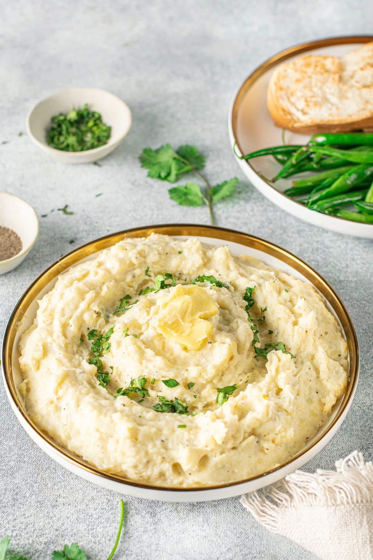 side dish bowl with overflowing mashed potatoes with parsley and butter on top