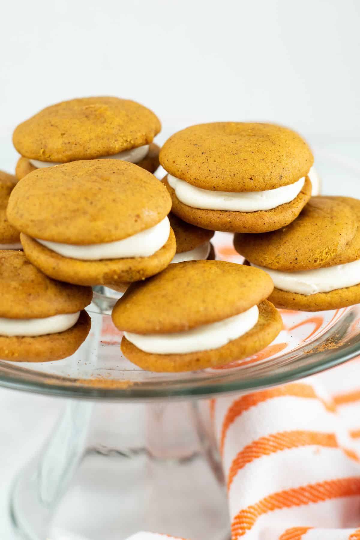 stacked, fluffy pumpkin whoopie pies with white frosting in the middle