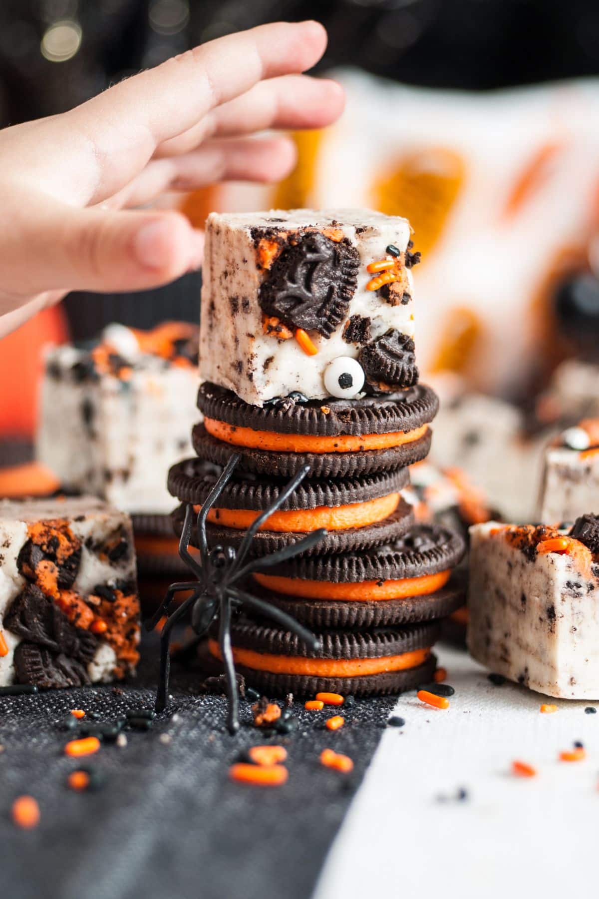 hand reaching for piece of fudge stacked on top of Halloween Oreos