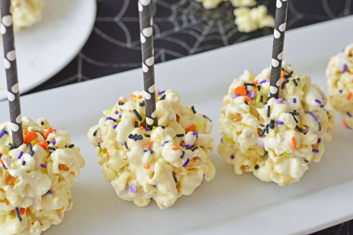 popcorn balls with straws and Halloween sprinkles