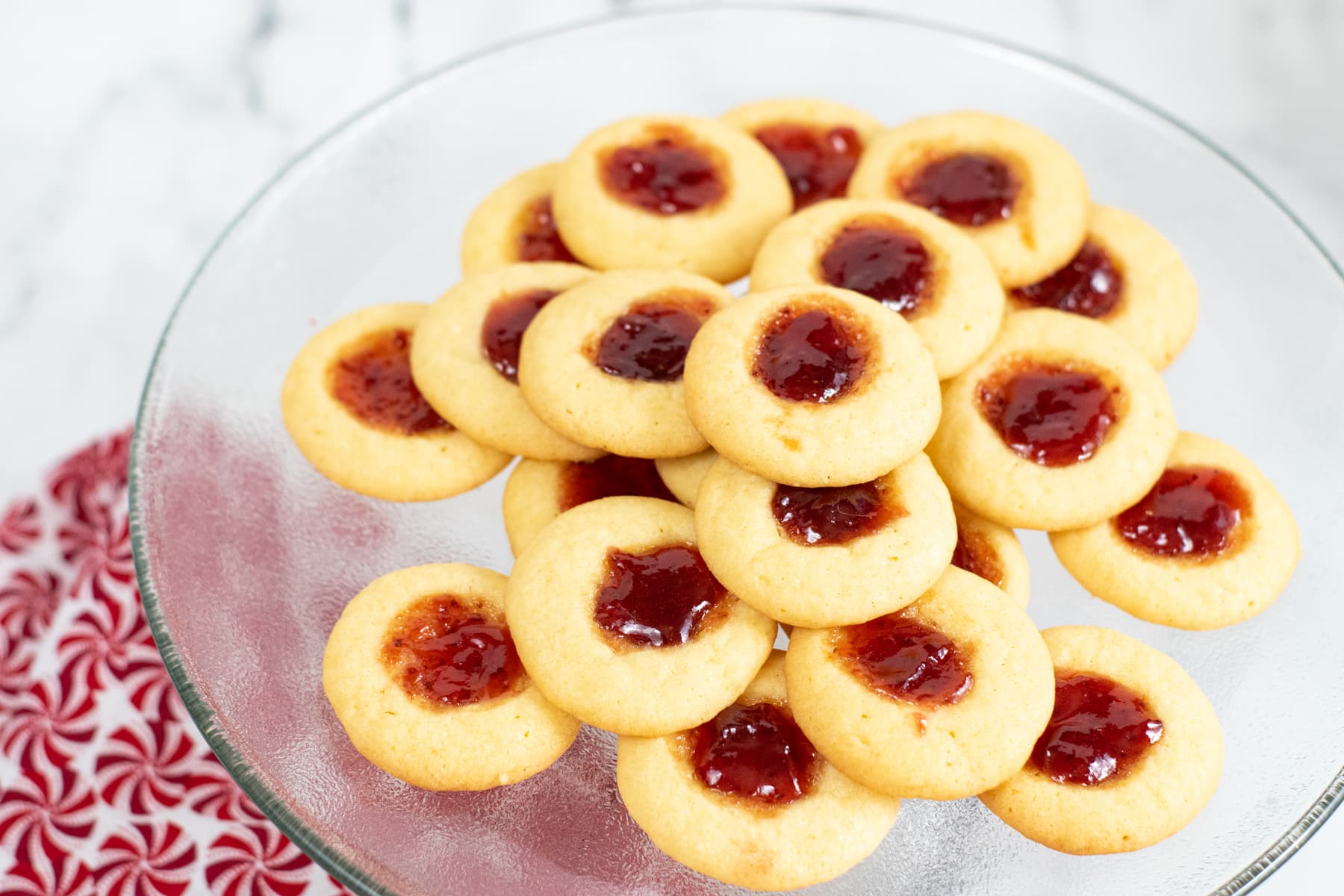 Bite sized Strawberry Thumbprint Cookies on a glass plate