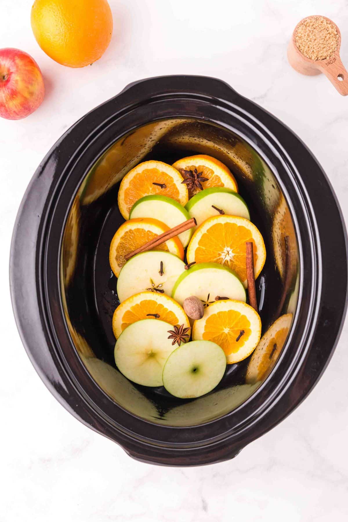 apple and orange slices with spices in crockpot