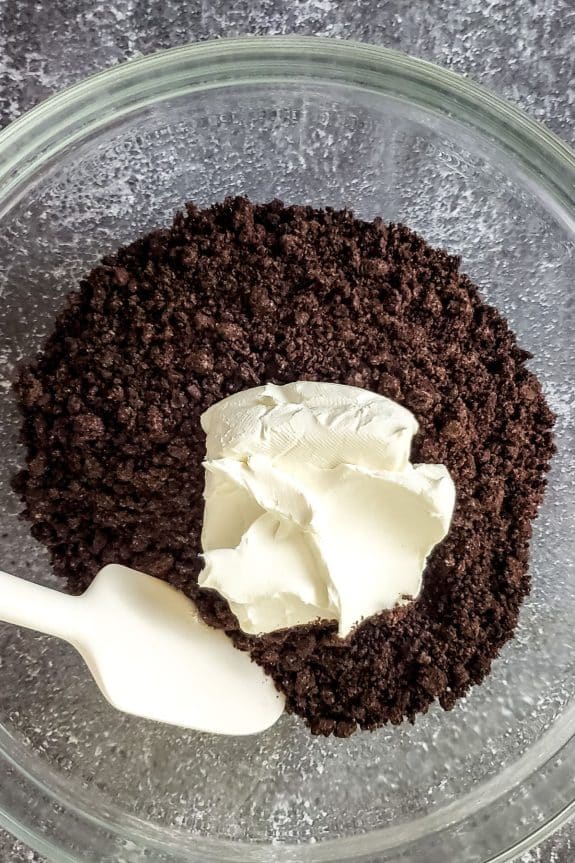 crushed oreos and cream cheese in mixing bowl