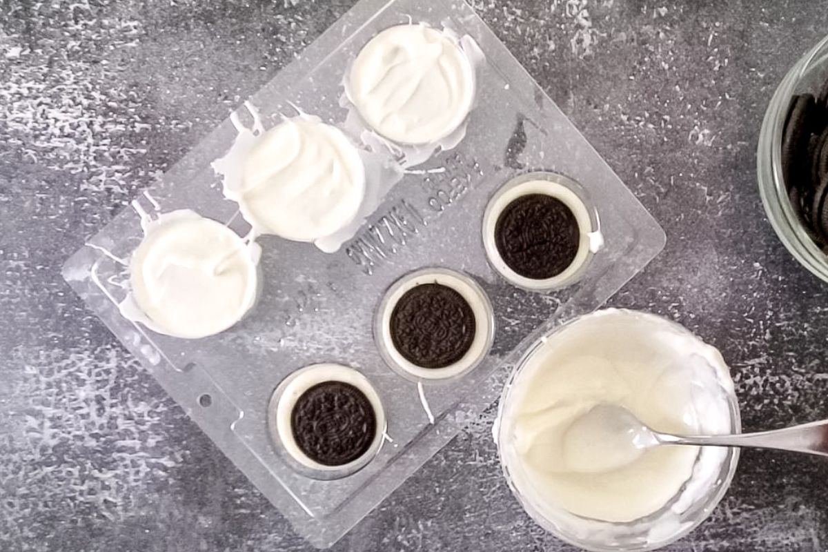 chocolate mold with three oreos sitting in white chocolate