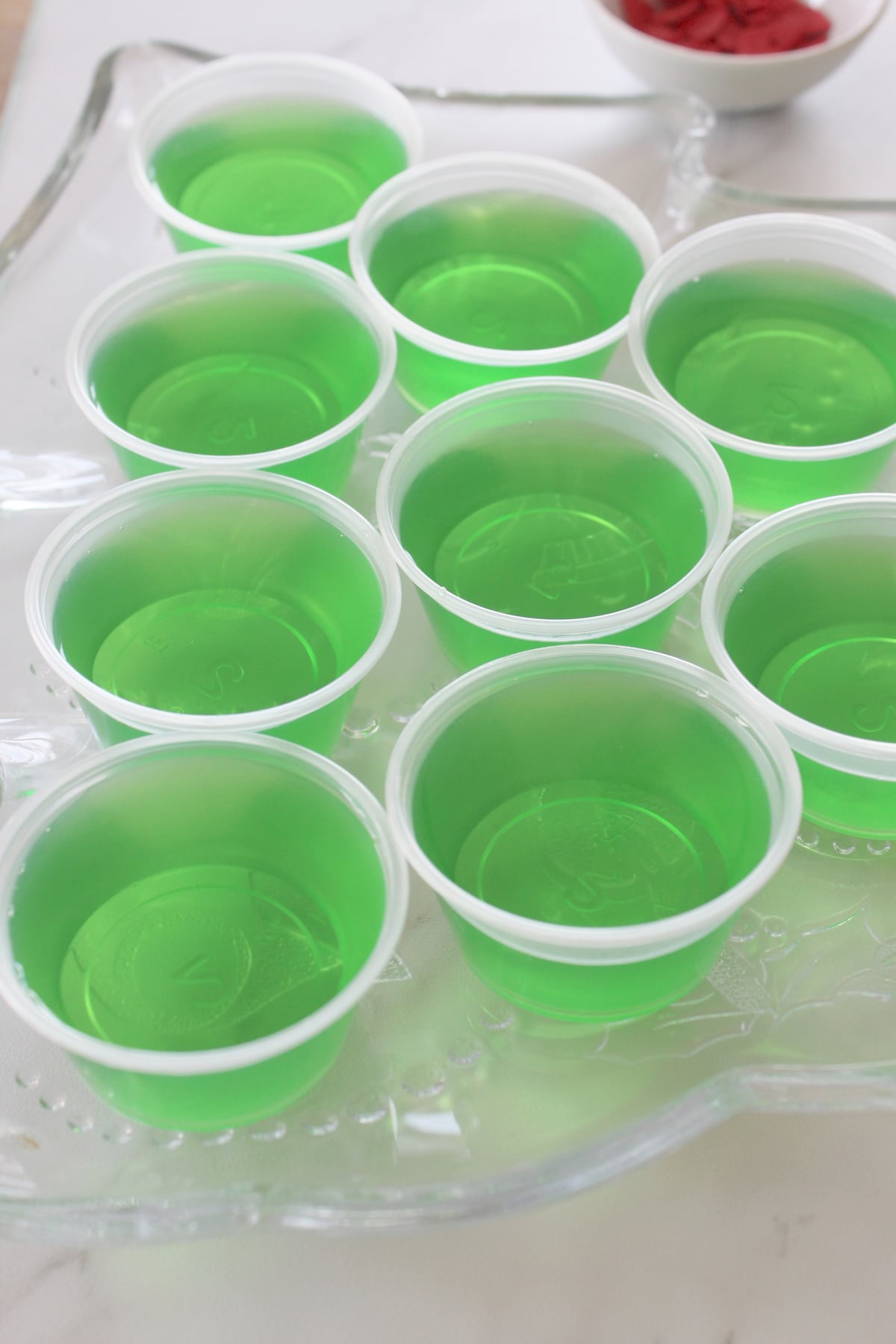 Adding some green gelatin on white cups is one of the process of making The Grinch Jello Shots