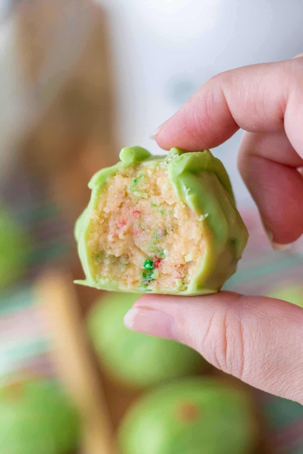 hand holding light green Grinch truffle with bite out