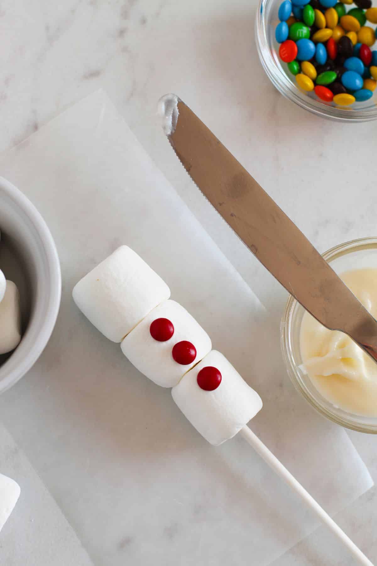 red candies on front of marshmallows on stick