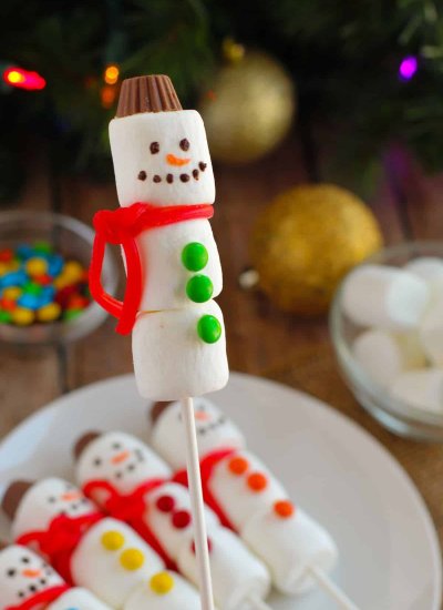 marshmallow snowman with candy buttons and red candy scarf on a stick
