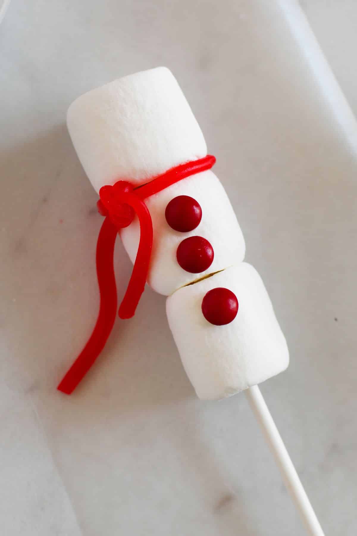 red licorice piece tied between first and second marshmallow on stick to look like a scarf