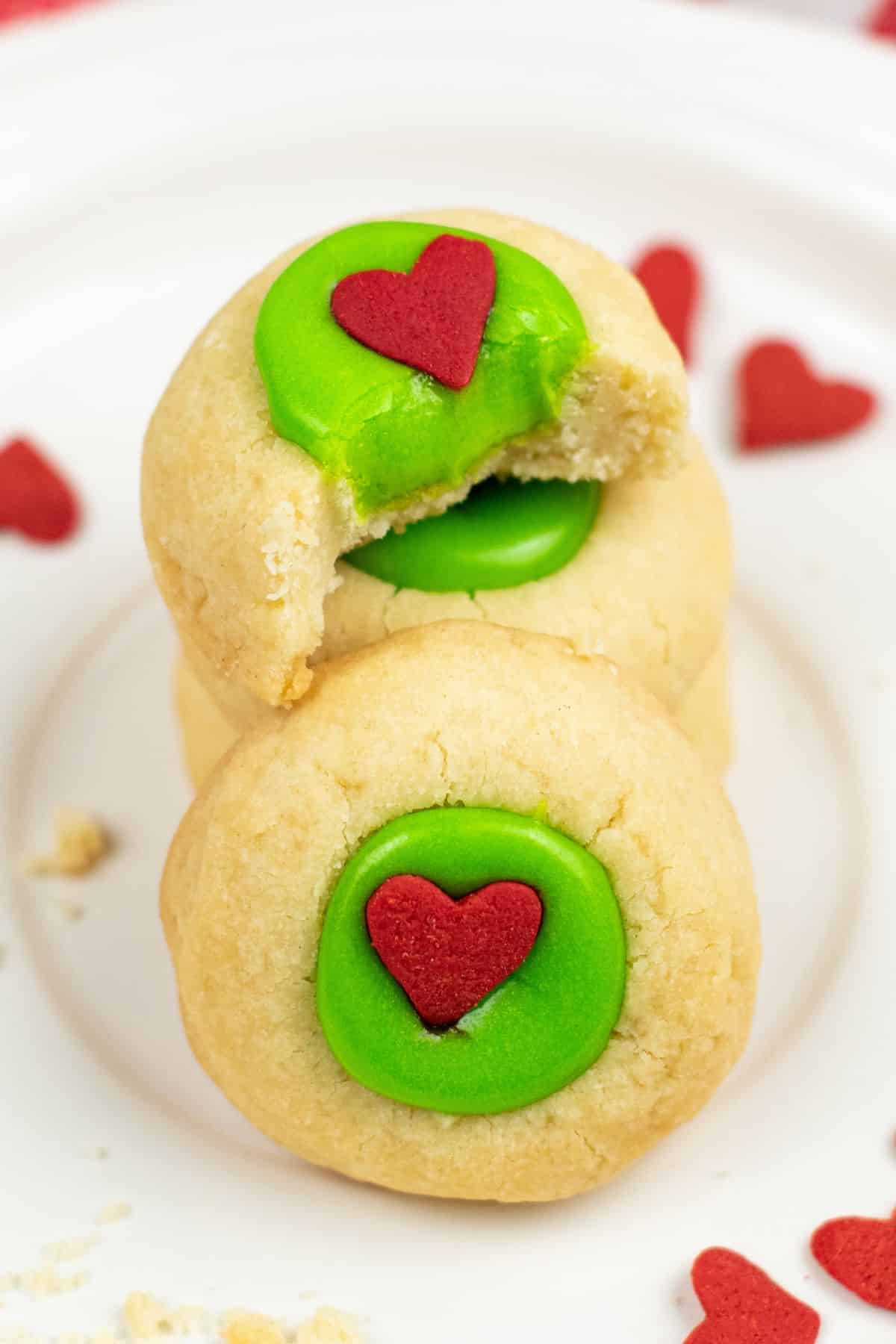 stacked Grinch thumbprint cookies with bite out of the top one