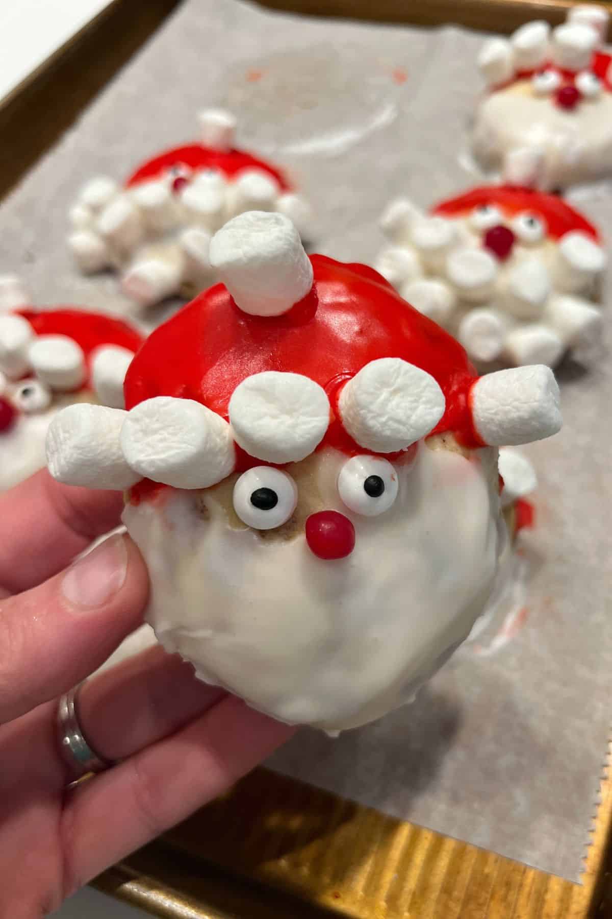 hand holding santa cinnamon roll with marshmallows as the fur on the hat