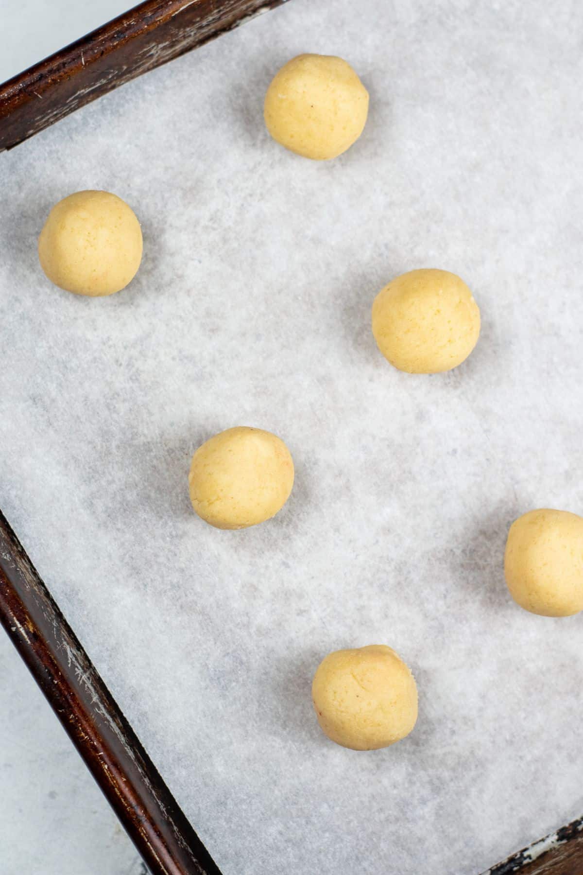 cookie balls on parchment-lined baking dish