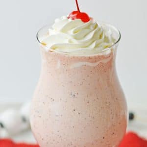 top half of pink milkshake with whipped cream and a cherry on top
