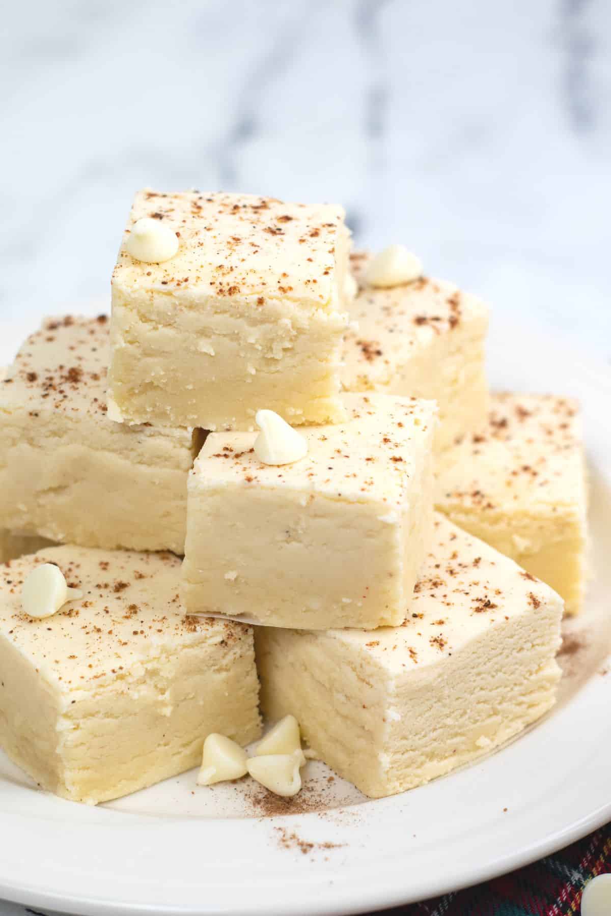 squares of eggnog fudge stacked on plate