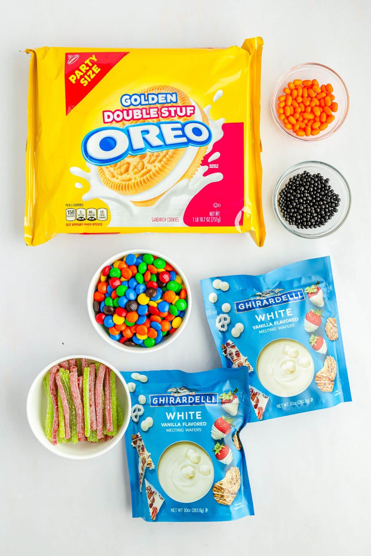 golden Oreos, white chocolate, colorful candies on white counter