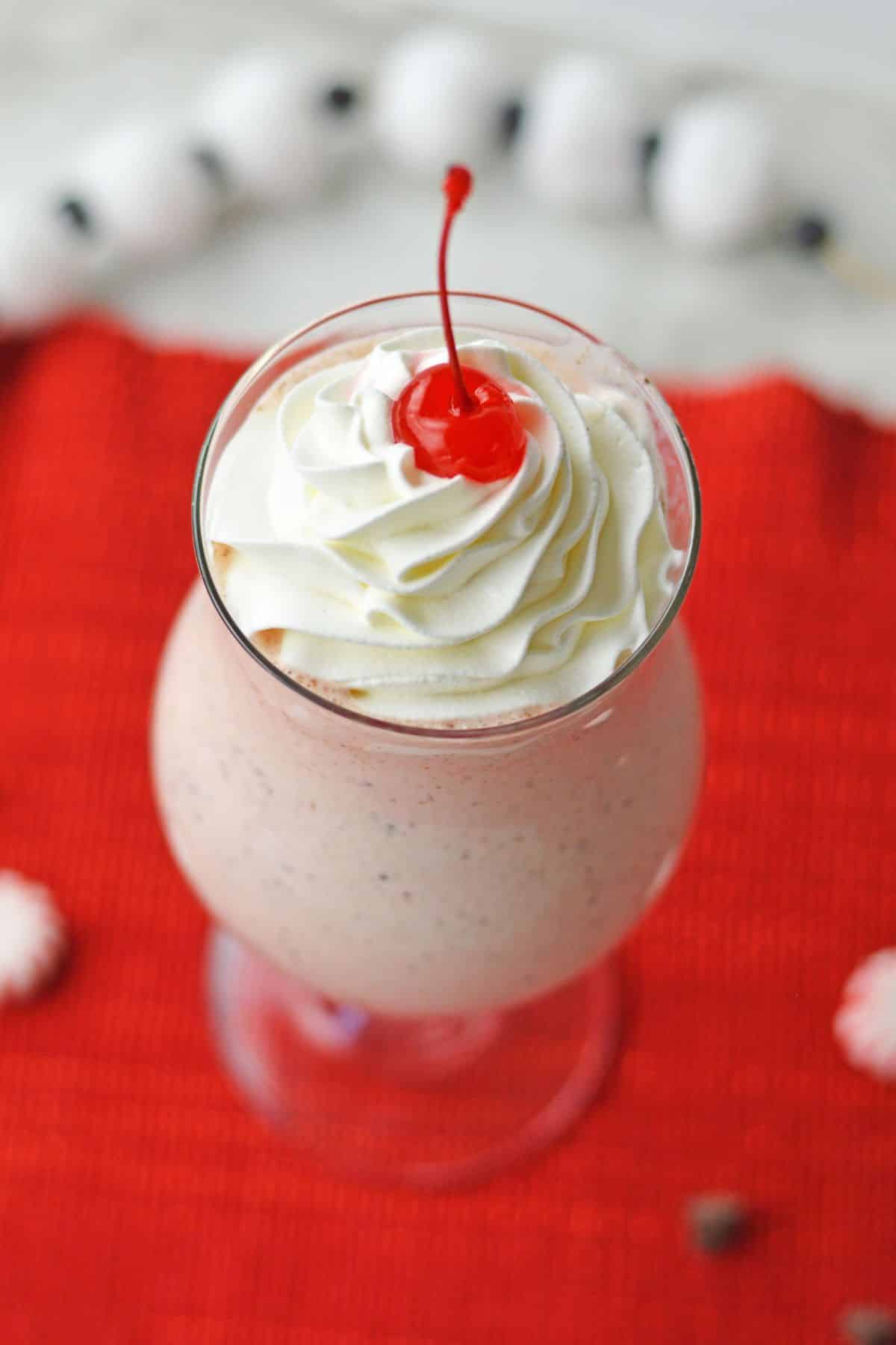 pink milkshake with whipped cream and a cherry