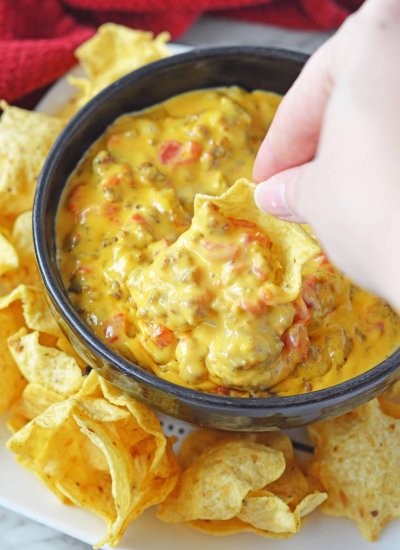 cheesy rotel dip with chip being dipped into the bowl