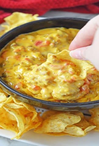 cheesy rotel dip with a chip dipped into it
