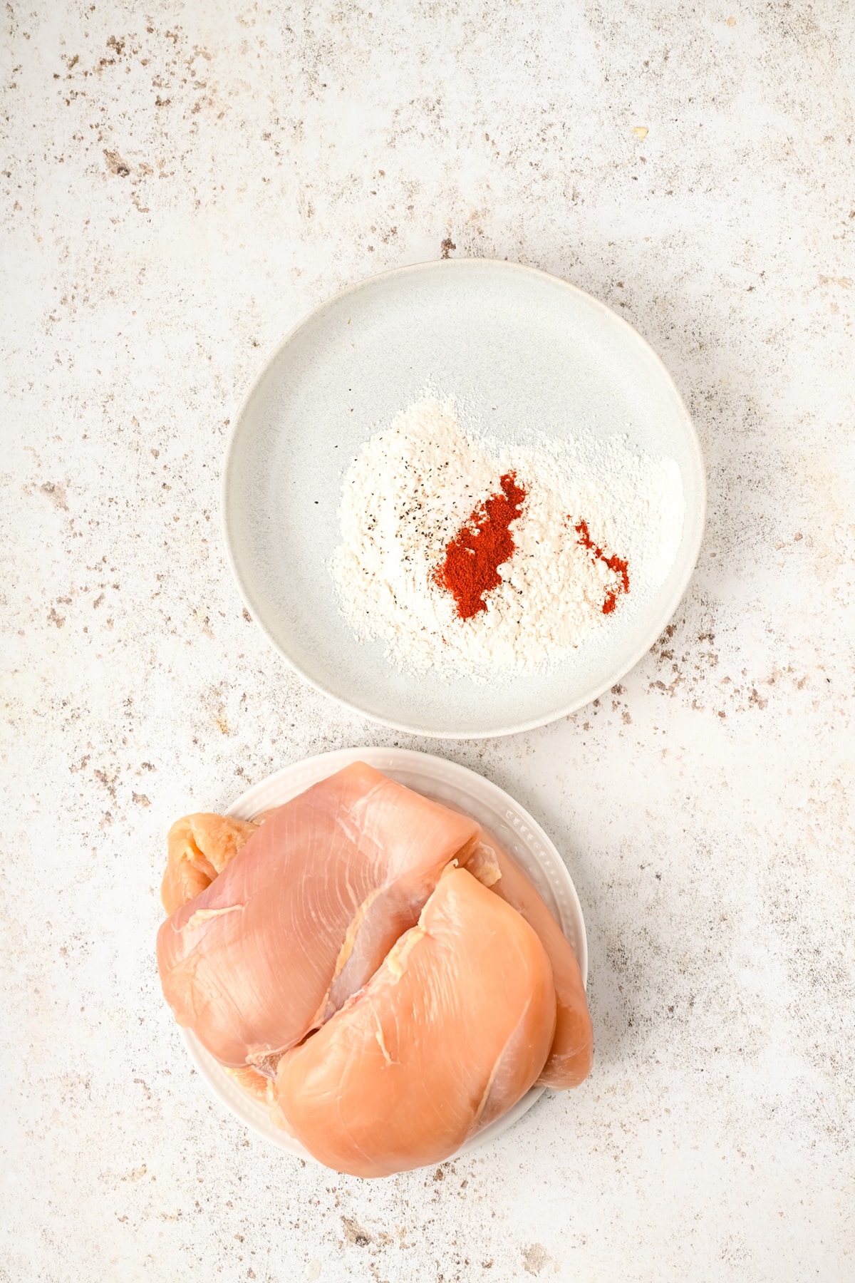 Chicken breast and a bowl of flour, paprika, salt, and pepper