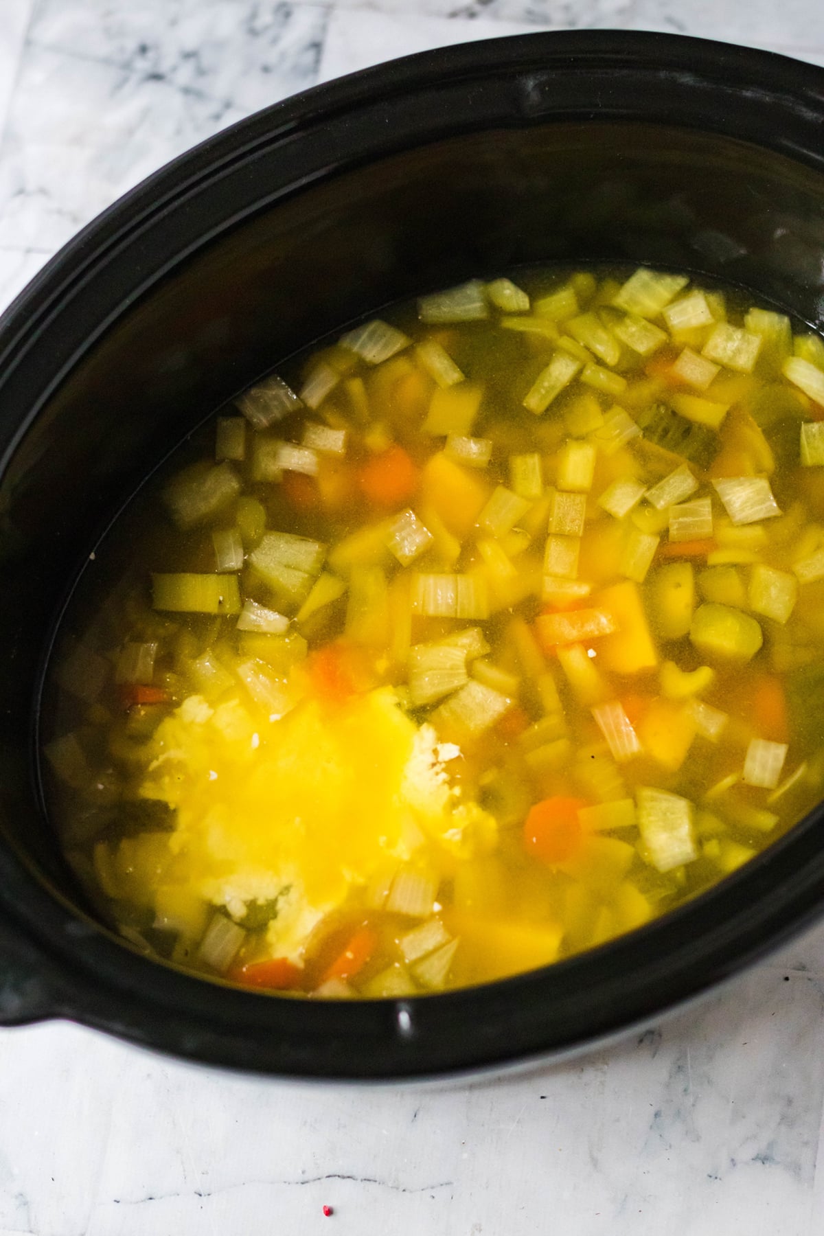 The pot is set to cook, chicken stock is added.