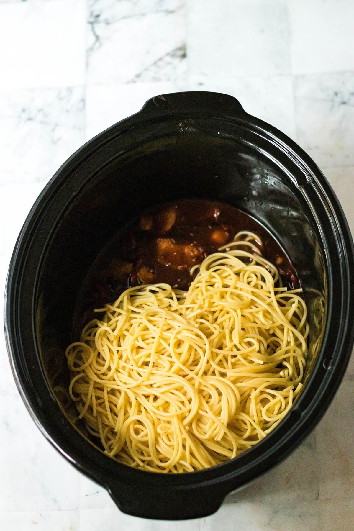 A cooked honey garlic chicken and pasta in a pot