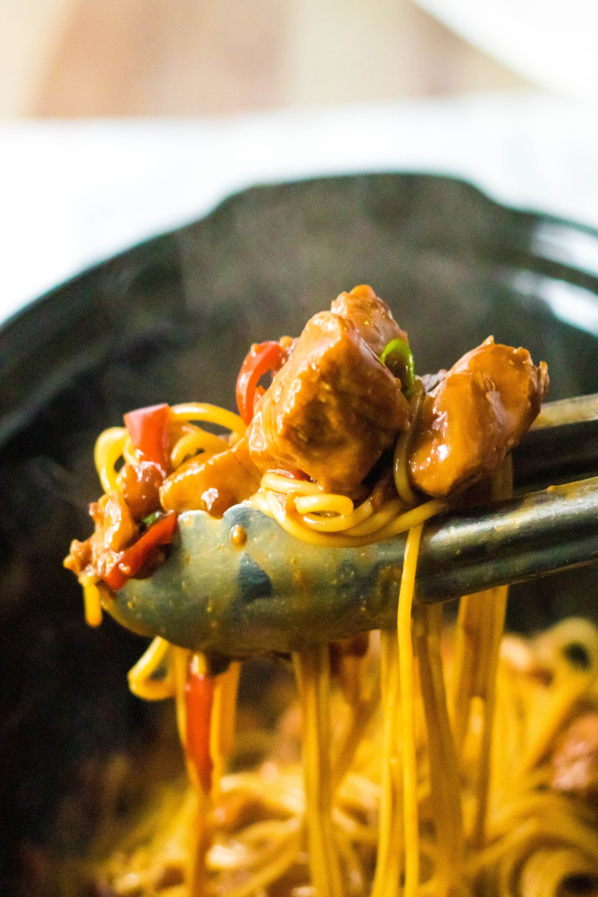 A tong holding a delicious slow cooker honey garlic chicken and noodles