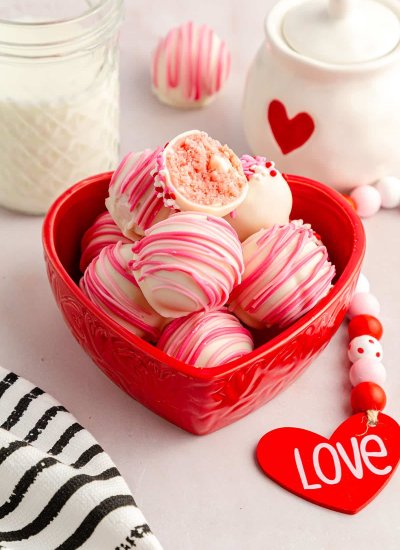 white and pink cheesecake balls in read heart-shaped bowl
