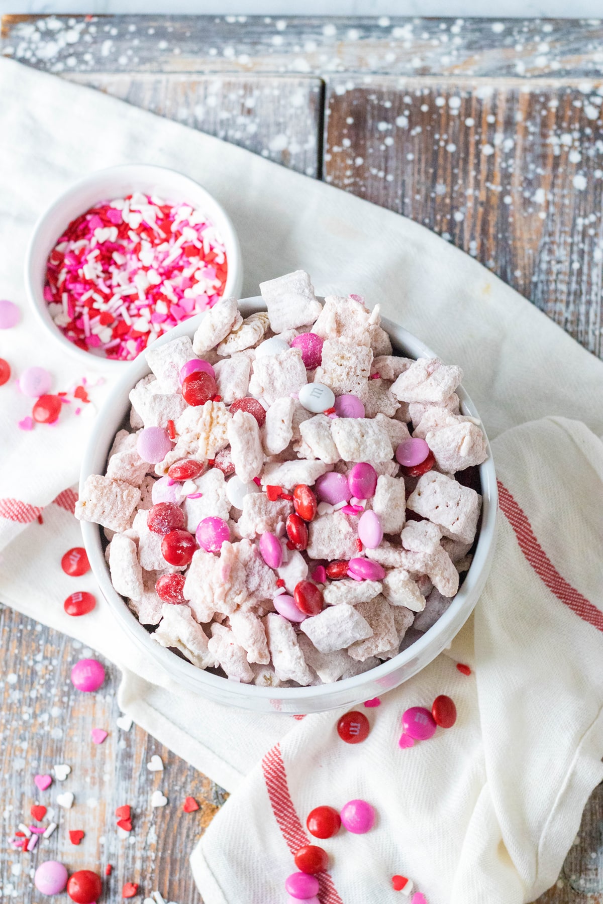 Plated strawberry puppy chow with toppings all over the table