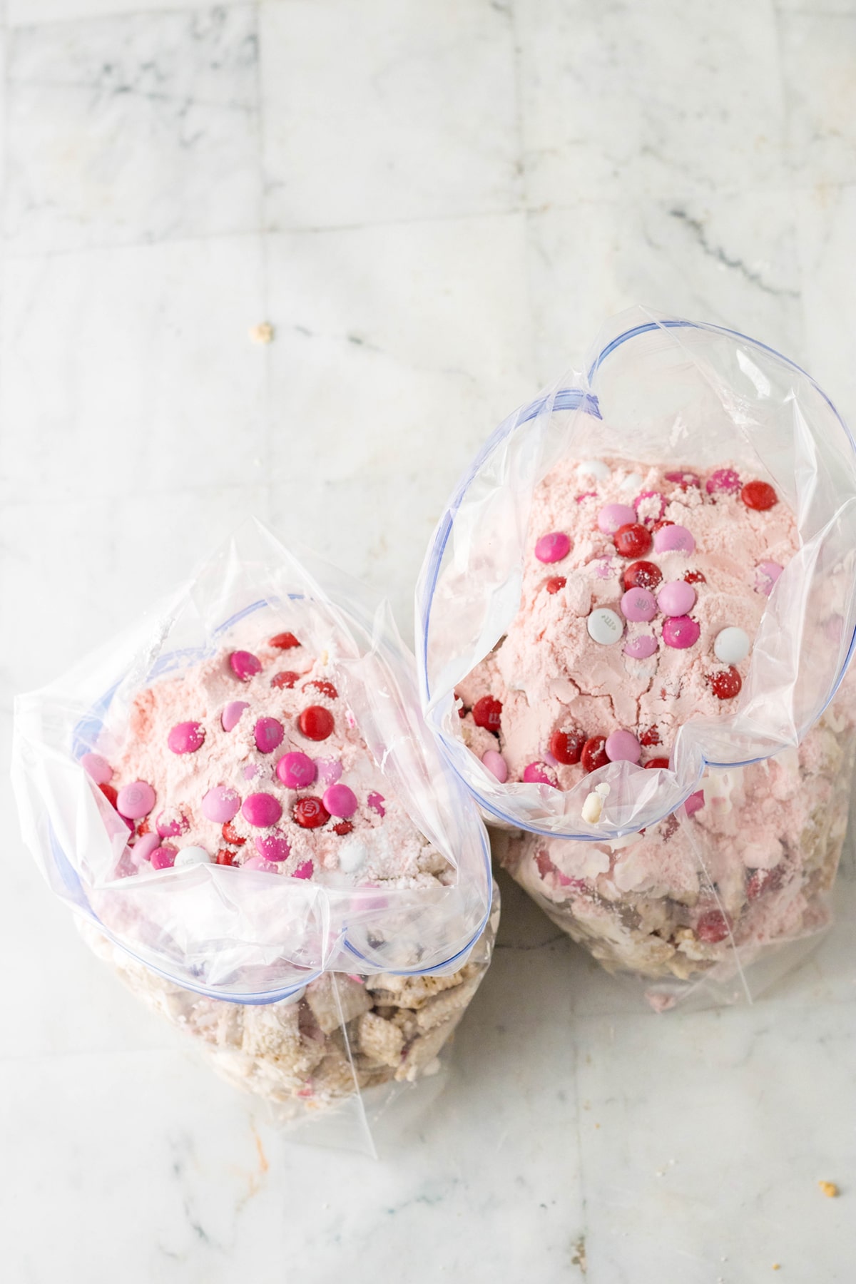 Two zip lock loaded with coated cereal with added  cake mix, m&m, and sprinkles