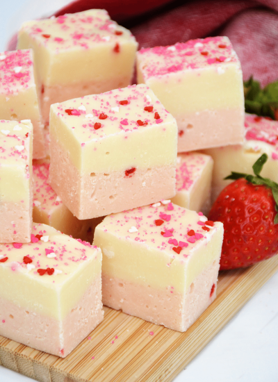 Pieces of White Chocolate Strawberry Fudge on a wooden board.