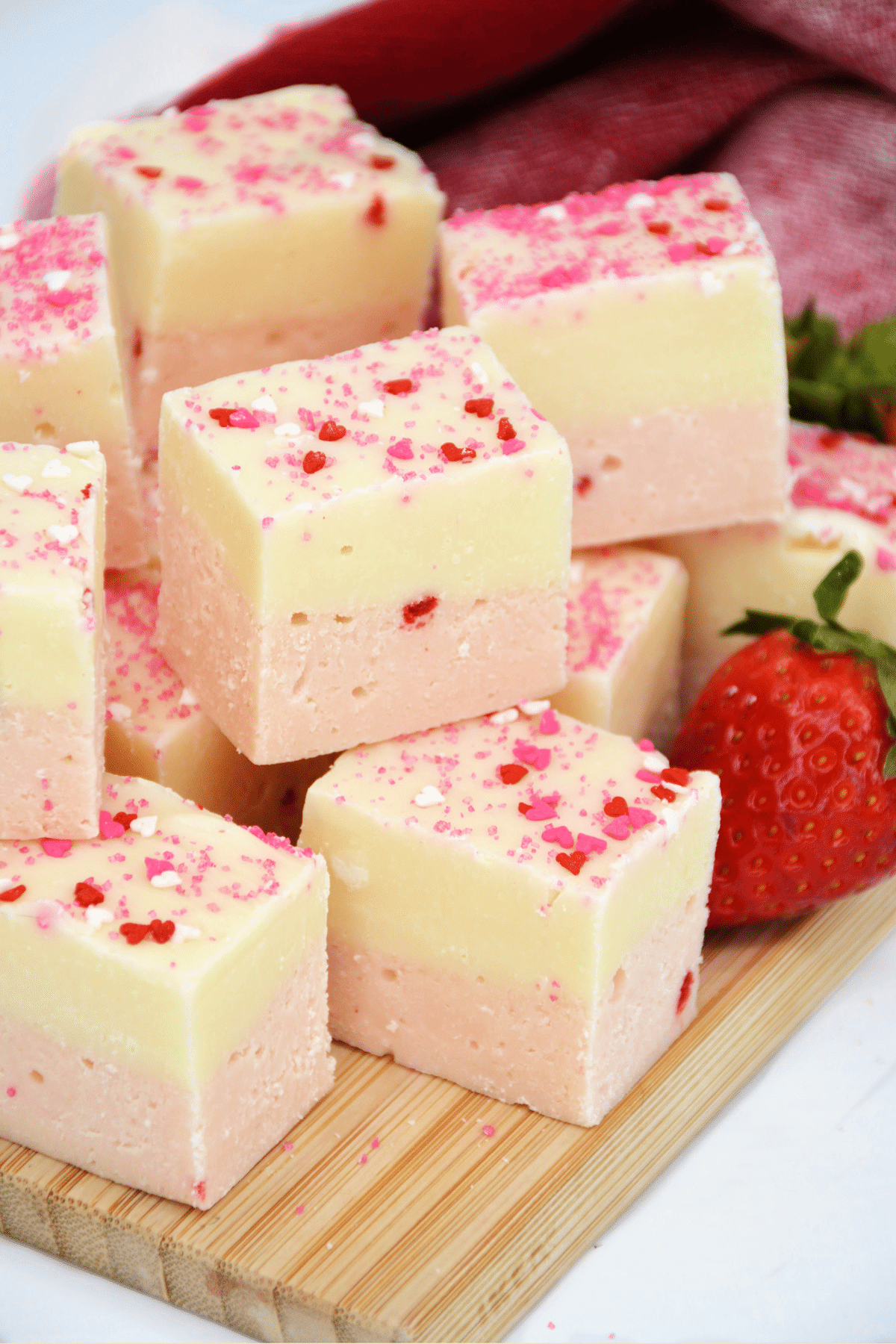 Pieces of White Chocolate Strawberry Fudge on a wooden board.