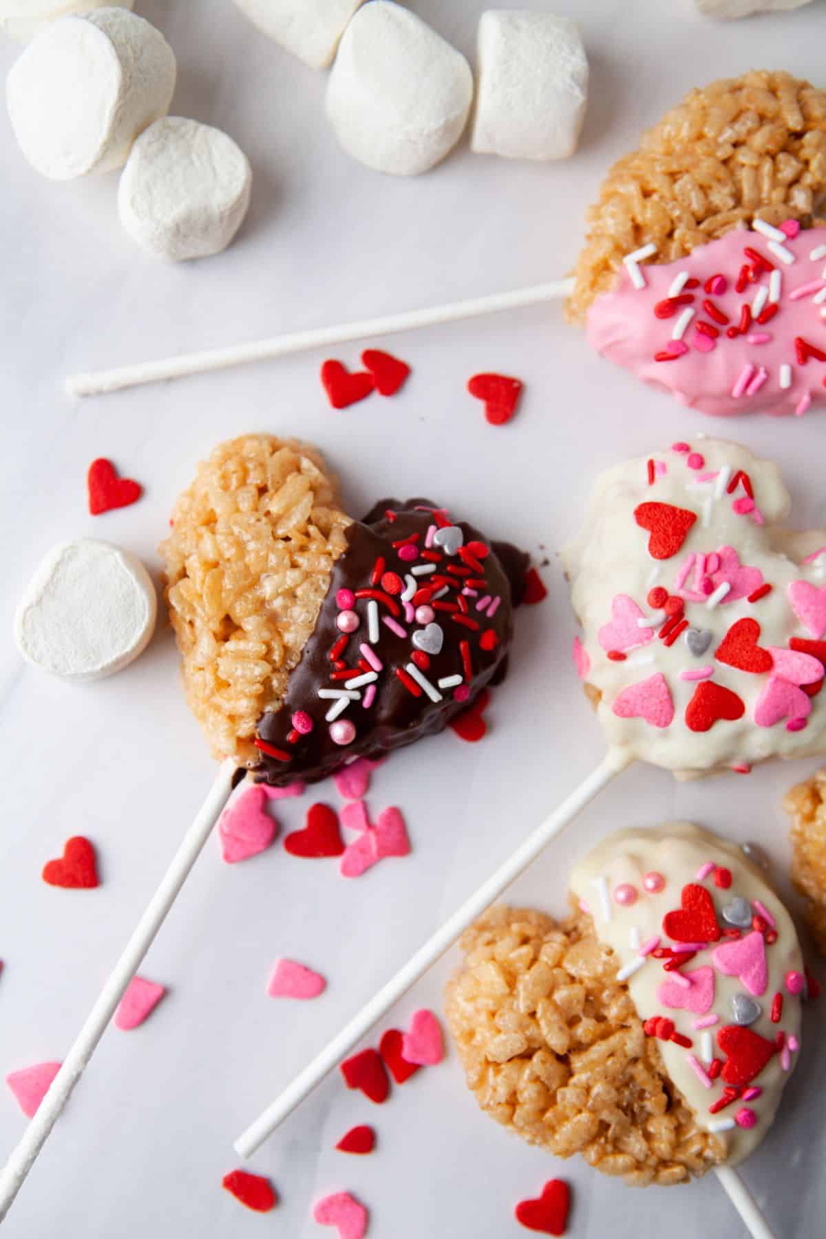 heart-shaped krispies pops on sticks with Valentine's sprinkles