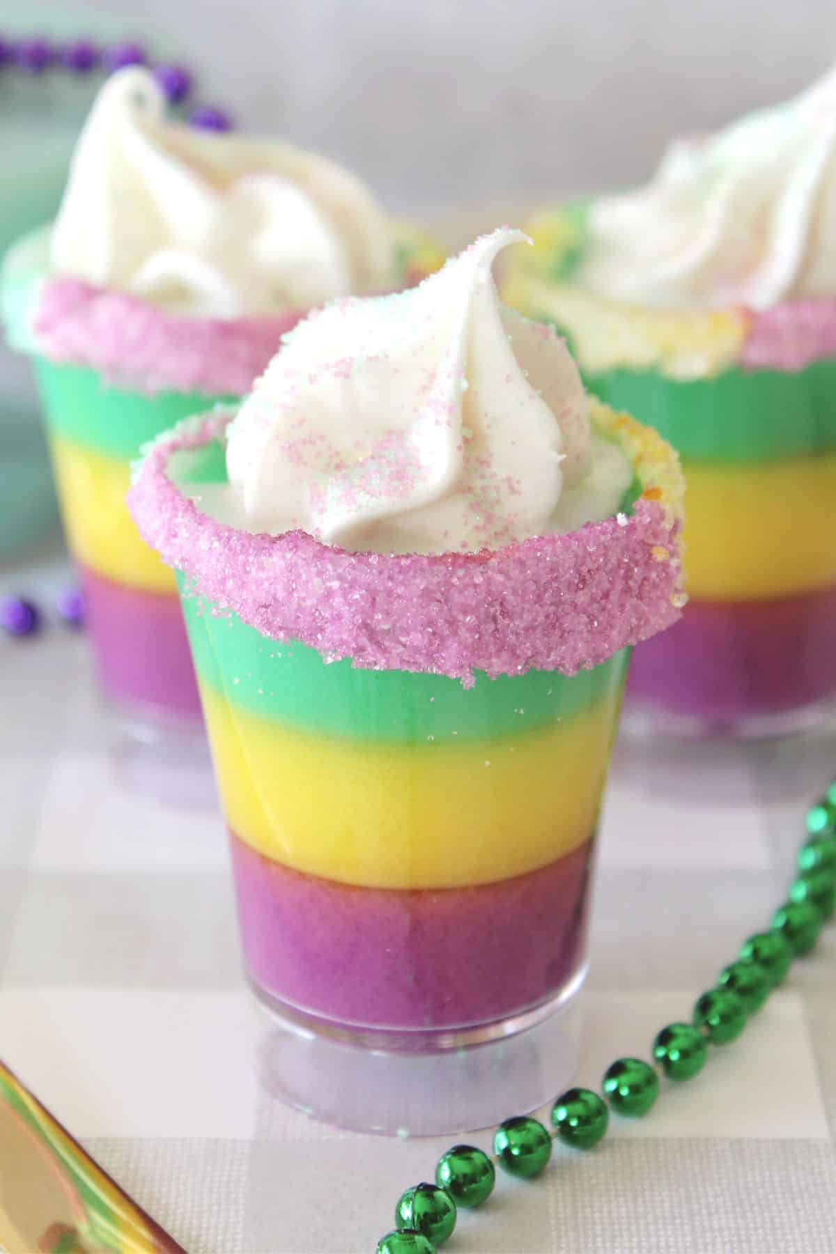 green, yellow, and purple Mardi Gras pudding shots with whipped cream