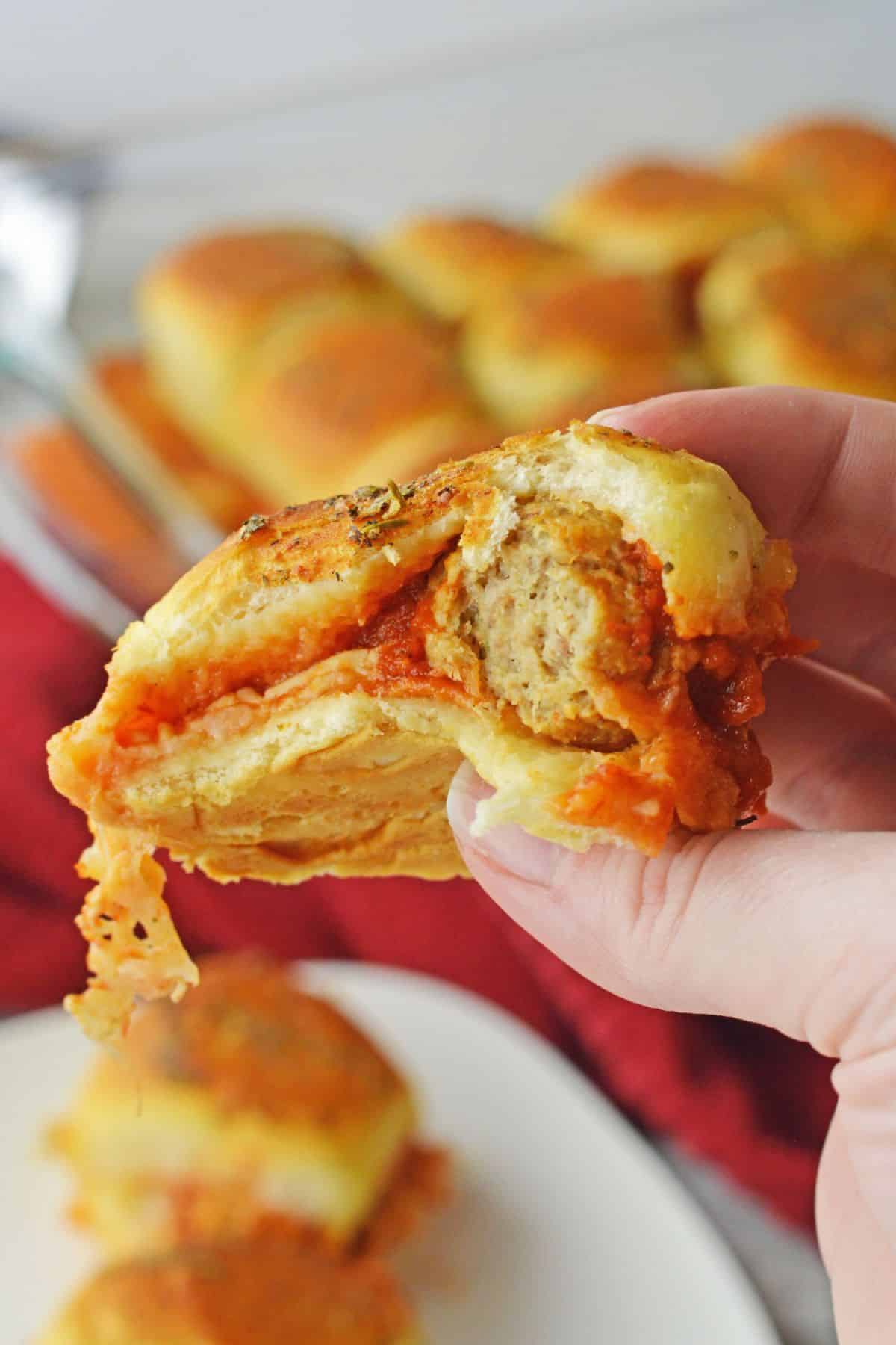 meatball inside rolls with sauce oozing out of roll