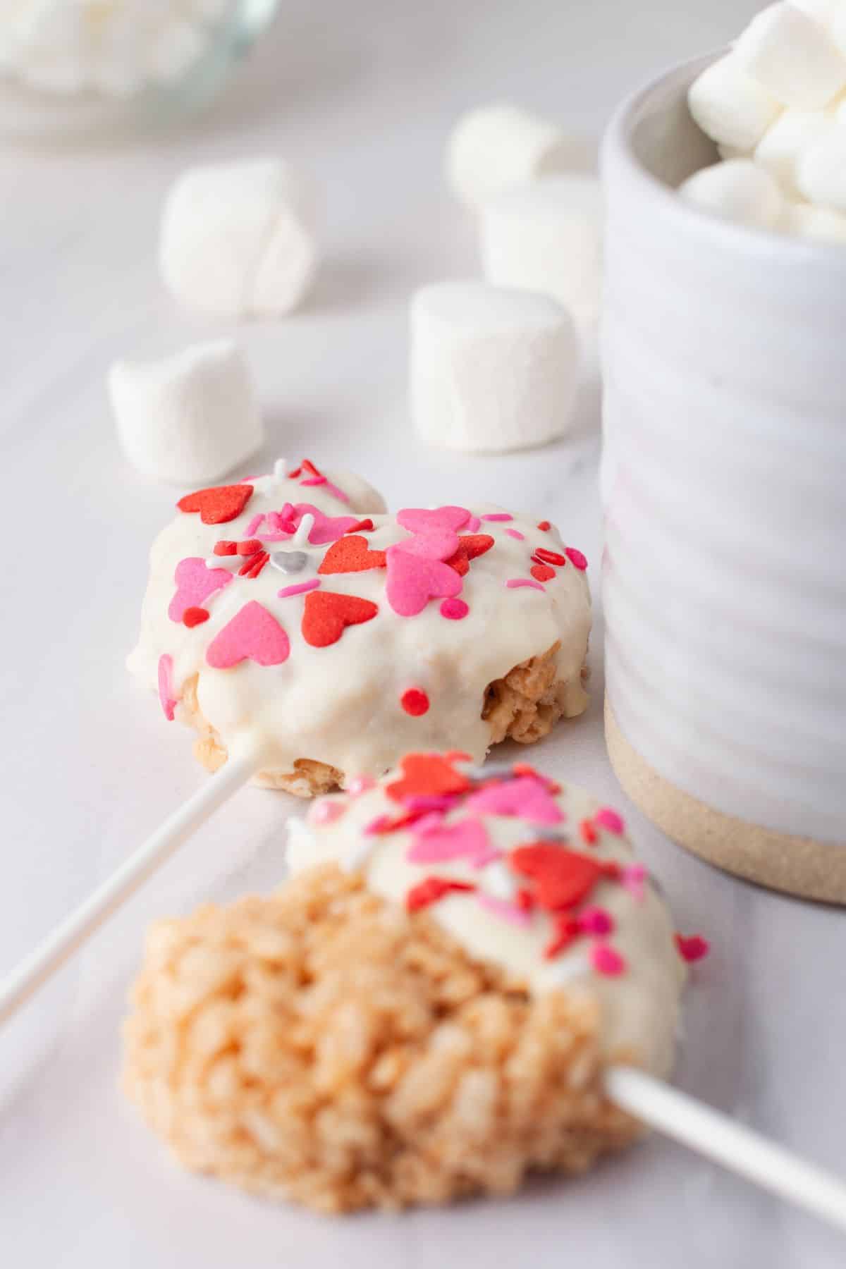 white chocolate with red sprinkles on heart krispies treat pops