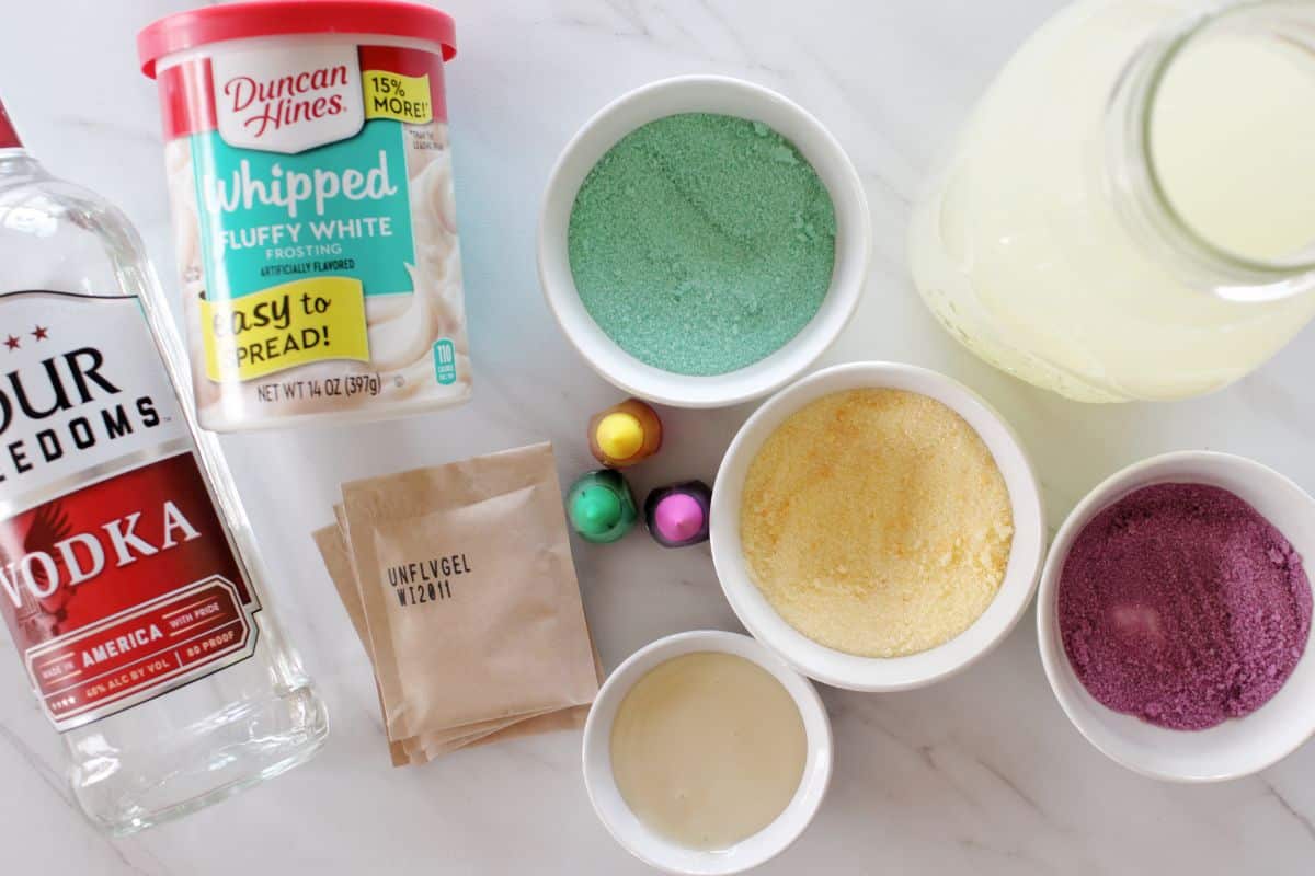 can of frosting, bottle of vodka, green, yellow, and purple jello powders, milk on counter