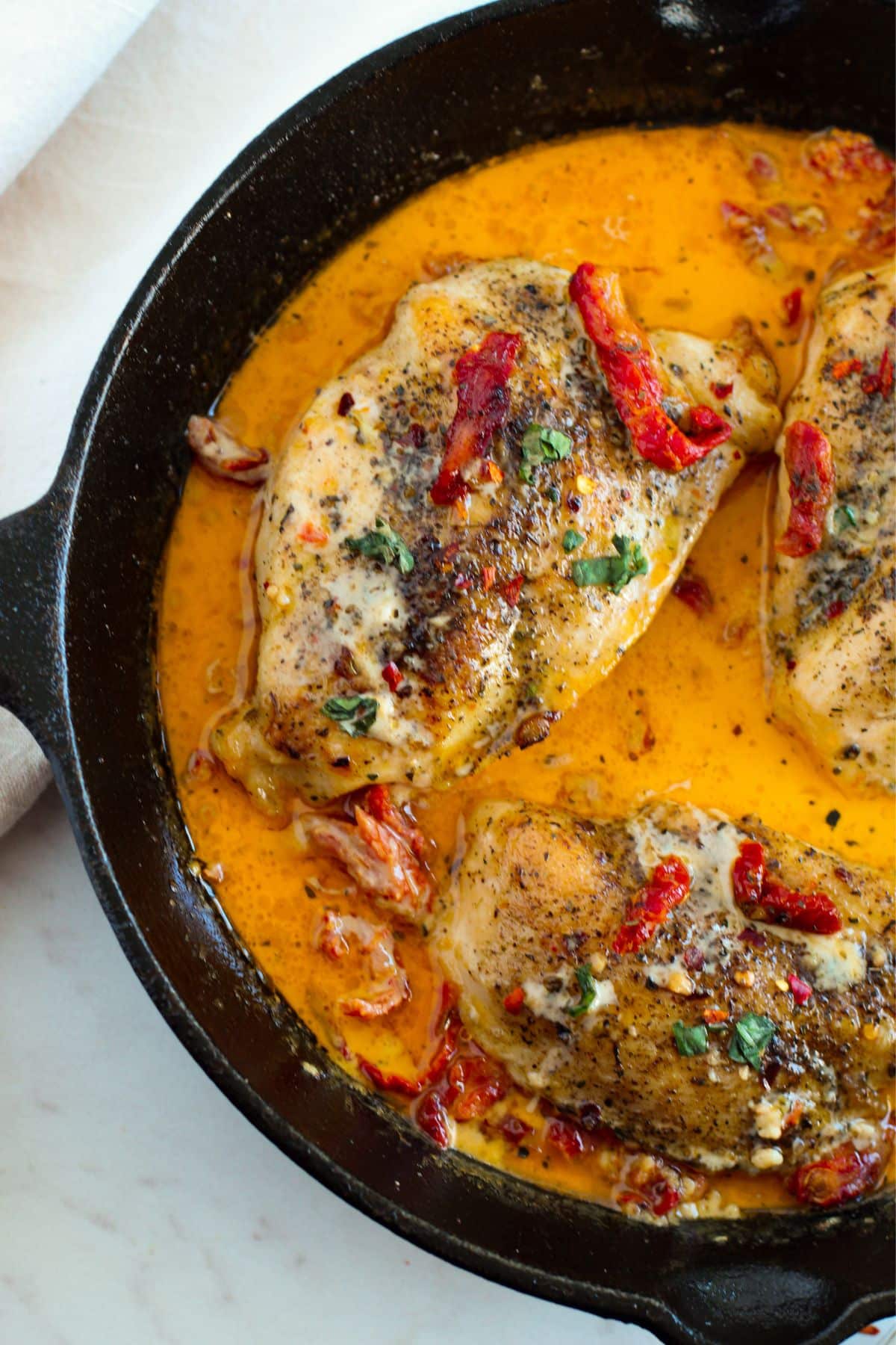 seasoned chicken breasts in tangy orange sauce in cast iron skillet