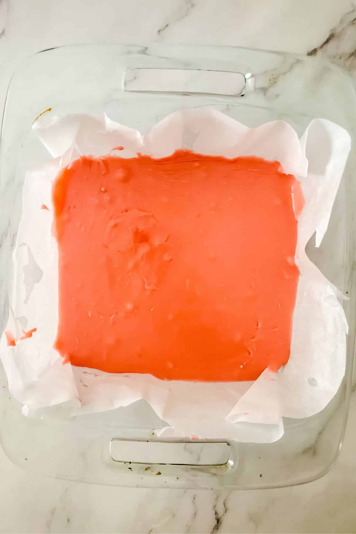 pink fudge in wax paper in square glass dish