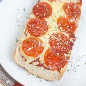 French bread pizza in a white plate sprinkled with basil and parmesan cheese