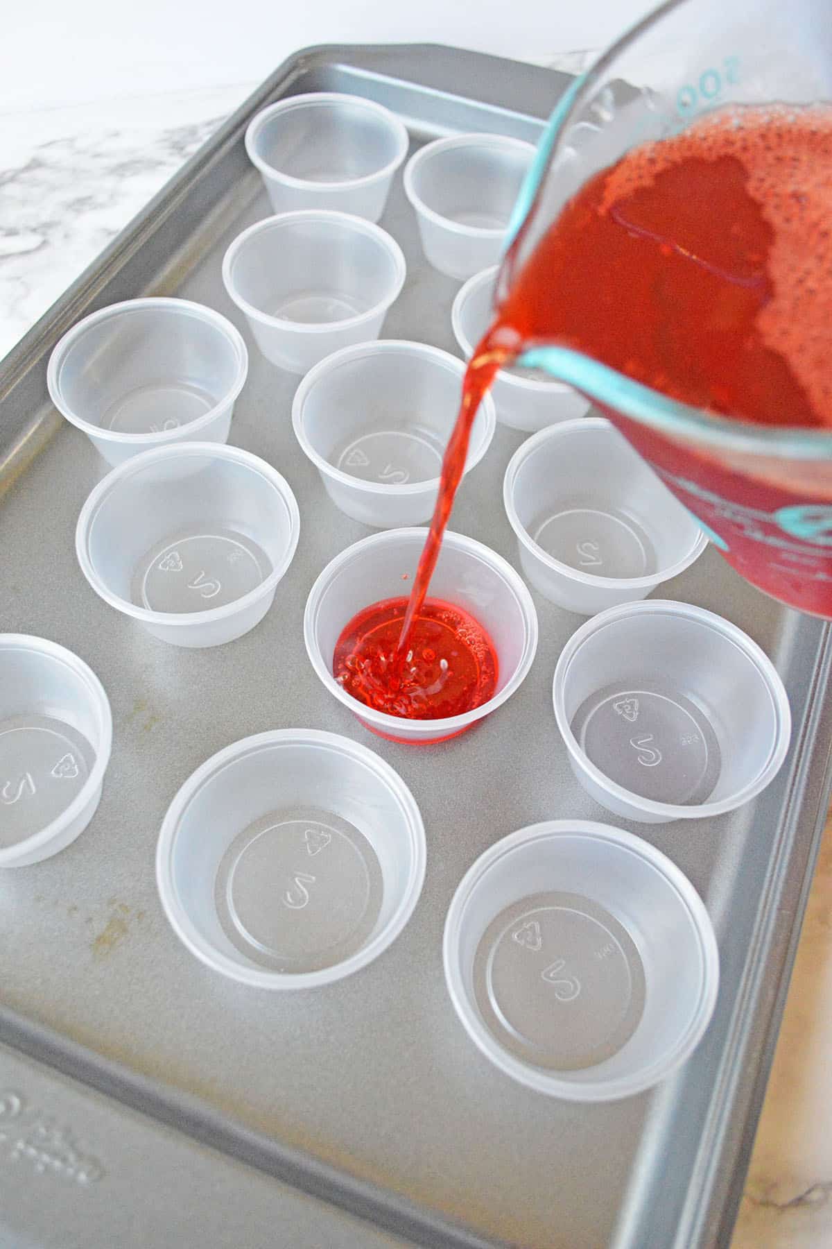 Small cups and mixture of Jello shot in red liquid color