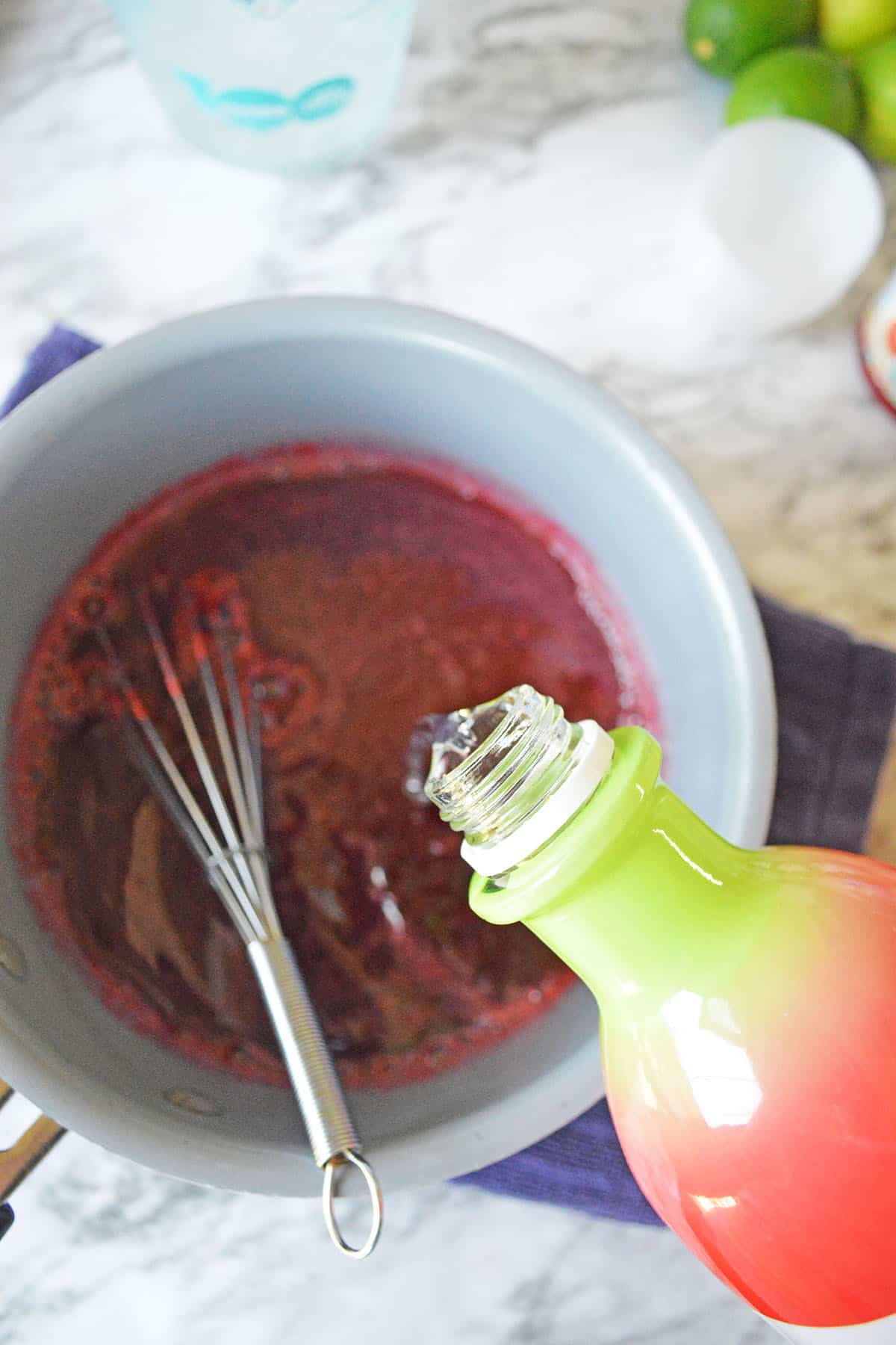Jello mix in red color with pouring vodka, wire whisk in the saucepan
