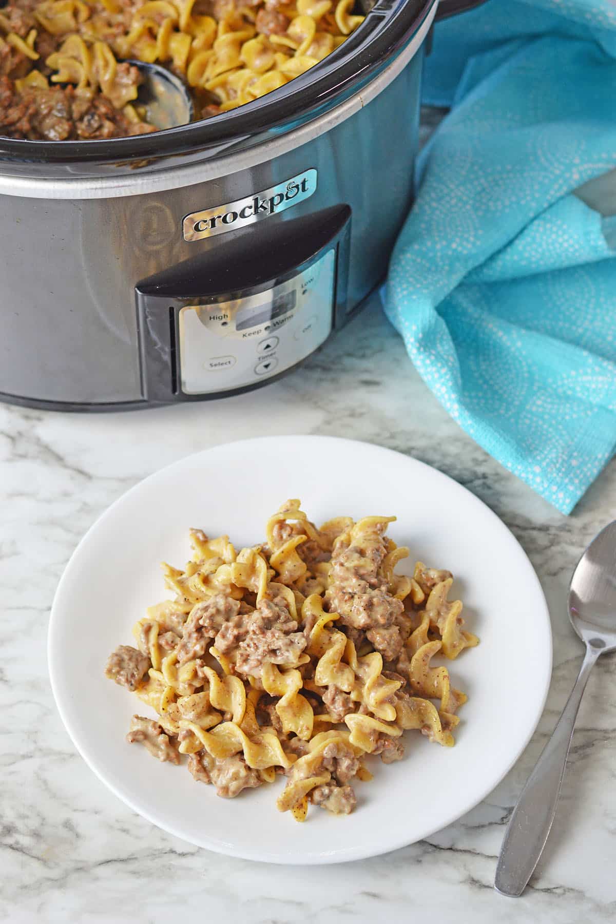 plate with noodles and ground beef with crockpot in background