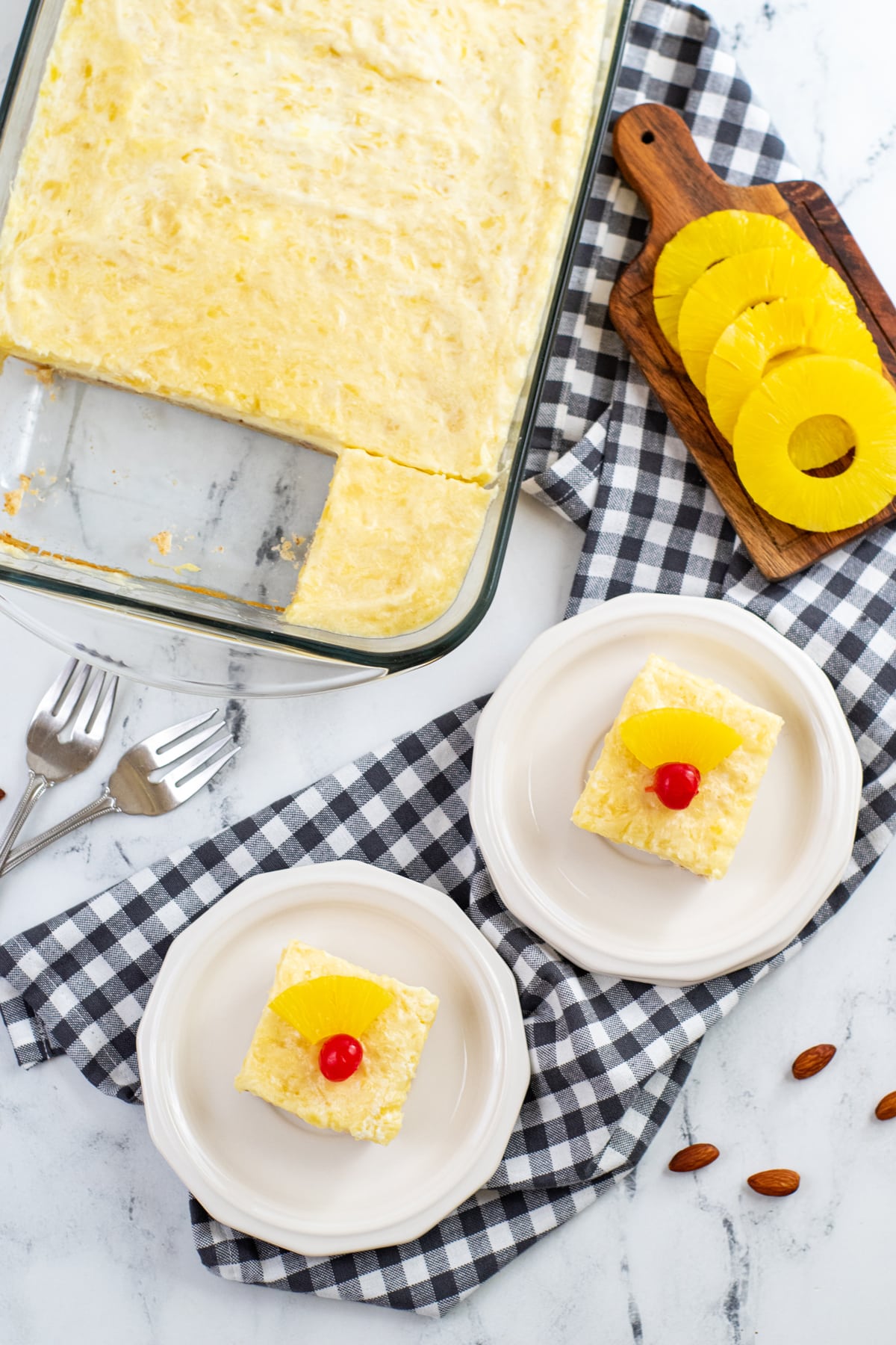 Pineapple Cheesecake Bars on a white plate with checkered linen
