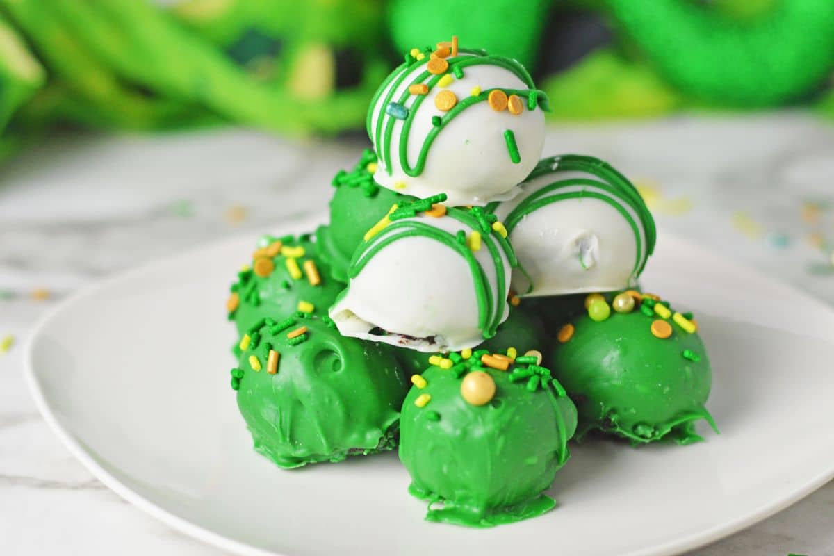 green and white candy coated Oreo balls on white plate