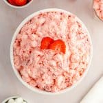A creamy bowl of strawberry fluff salad with slices of strawberry on top