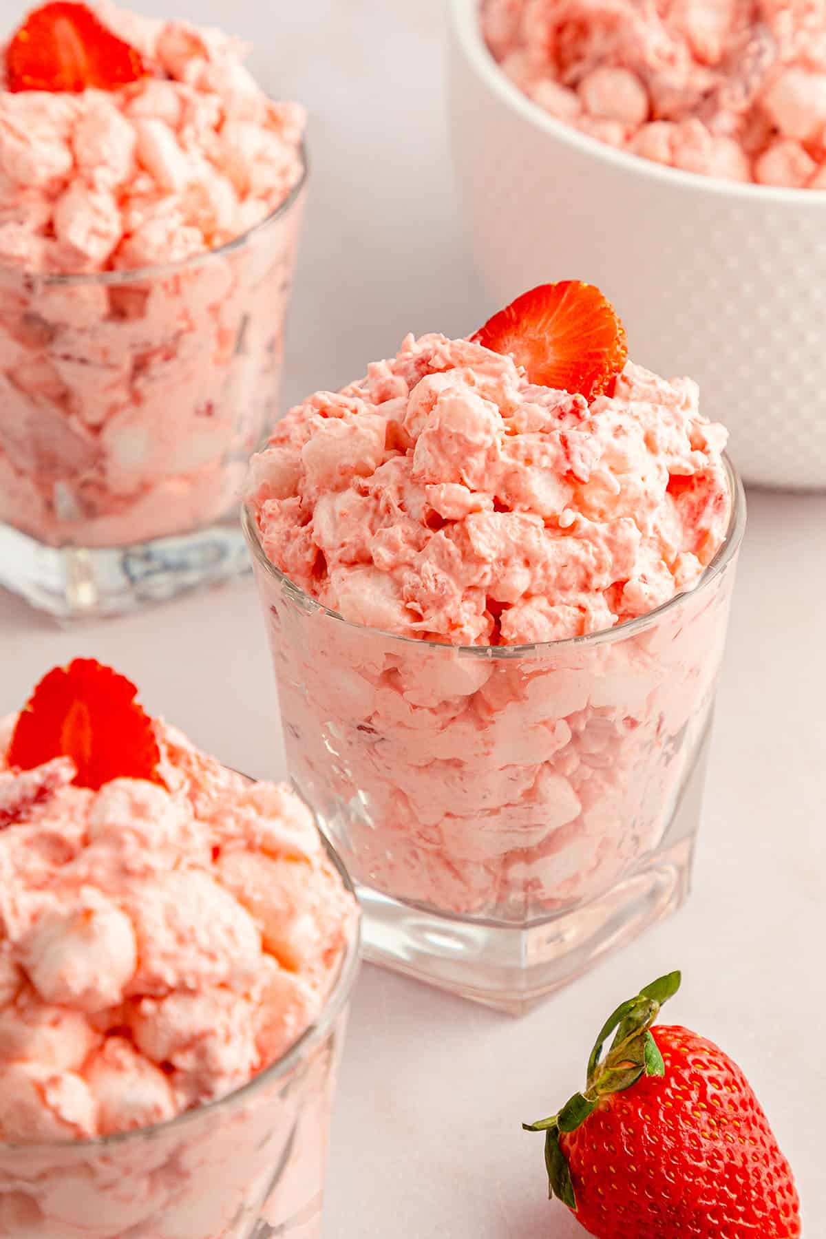 Strawberry fluff salad in a glass cup with a strawberry slice on top