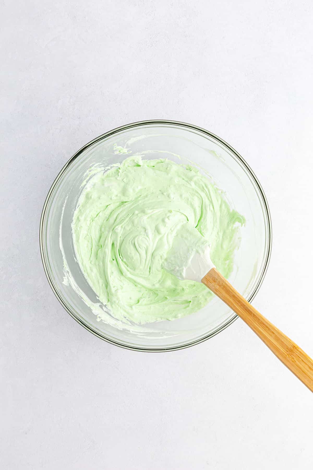 A creamy consistency pudding mixture in light green color with spatula