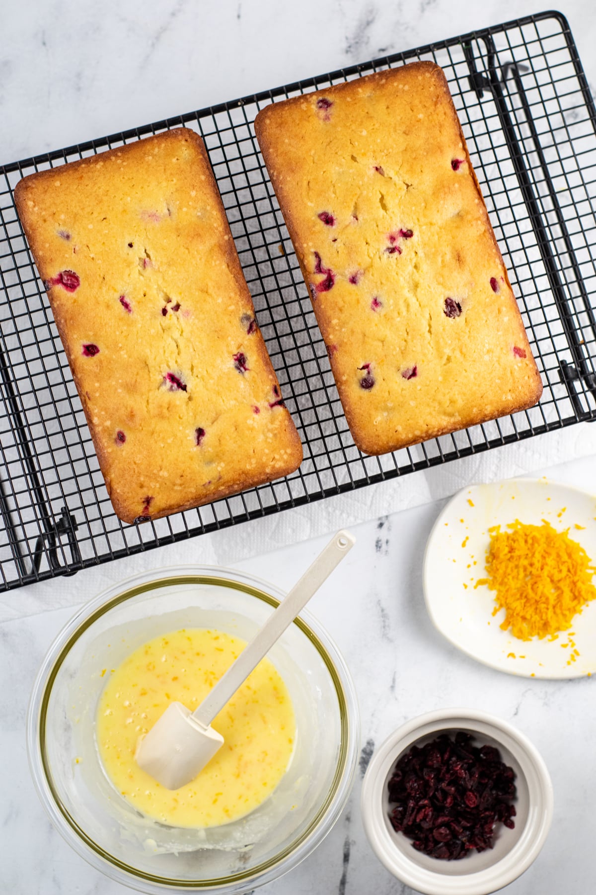 Loaves of Cranberry Orange Pound Cake on a rack with ingredients on the side