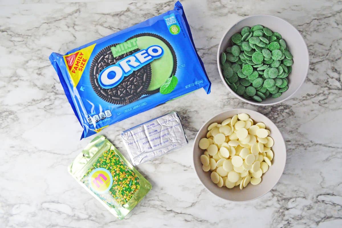 package of mint Oreo cookies, block of cream cheese, green and white candy mints, and green sprinkles